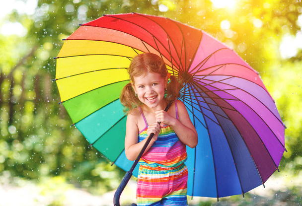 Menina feliz criança ri e joga sob chuva de verão com um guarda-chuva
 - Foto, Imagem