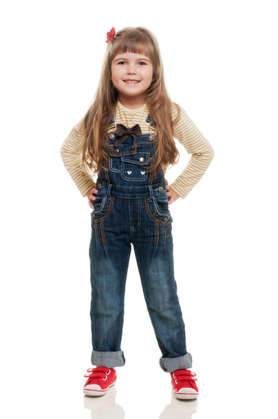 Cute little girl wearing jeans overall posing in studio and smil - Фото, зображення
