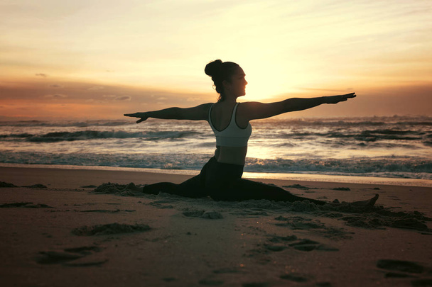 sportliche junge Frau praktiziert Yoga am Strand - Foto, Bild