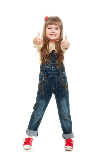 Cute little girl wearing jeans overall posing in studio showing - Foto, imagen