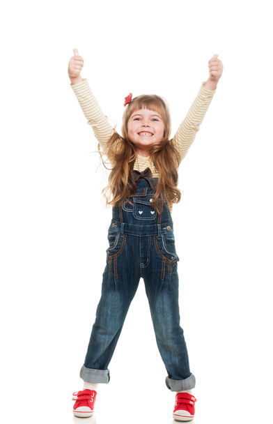 Cute little girl wearing jeans overall posing in studio howing o - Foto, Imagem