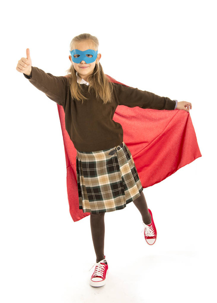7 or 8 years old young female child in super hero costume over school uniform  performing happy and excited isolated on white background  - Fotografie, Obrázek