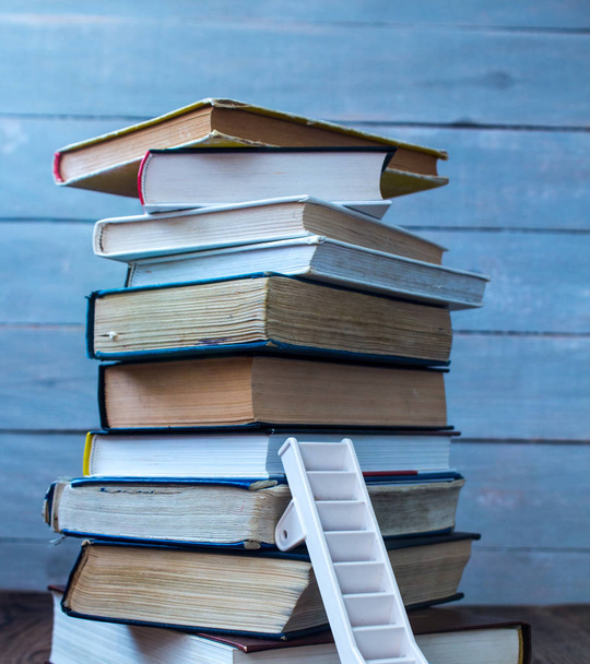 ladder on pile of old books on wooden background - Foto, Imagem