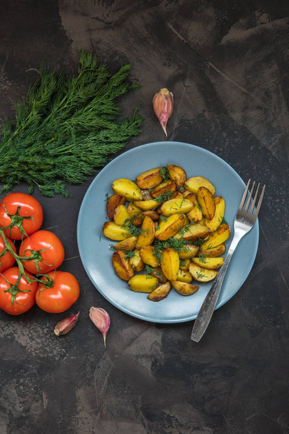 Жареный картофель, зеленый, помидоры и чеснок на темном backgr
 - Фото, изображение