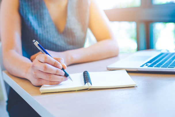 Mão feminina está escrevendo no bloco de notas com caneta no escritório
. - Foto, Imagem