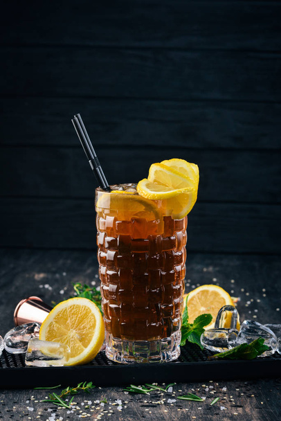 Alcohol cocktail Long Island. On a black wooden background. - 写真・画像