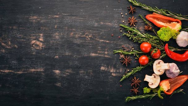The background of cooking. A set of spices and fresh vegetables. Top view. Free space for your text. On a wooden background. - Foto, Imagem