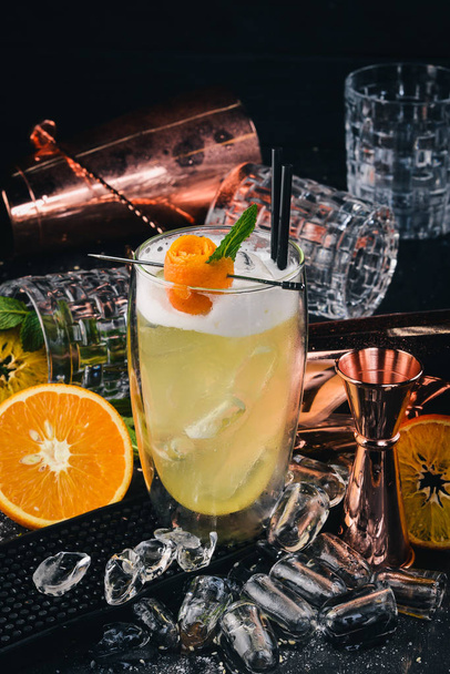 Alcohol cocktail Pinacolada. Orange, liquor, ice. On a black wooden background. - Fotó, kép