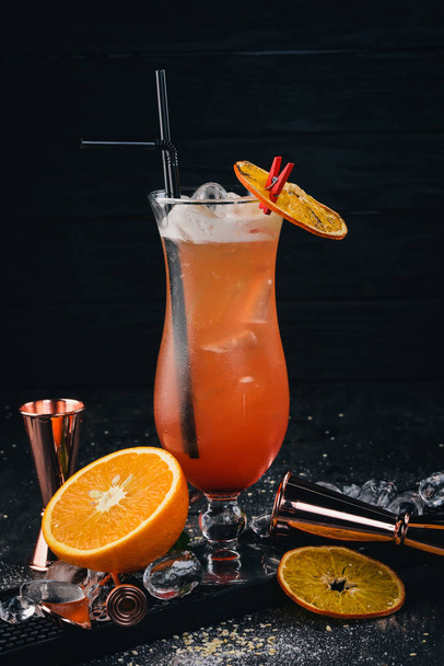 Alcoholic cocktail Sex on the beach. Orange. On a black wooden background. - 写真・画像