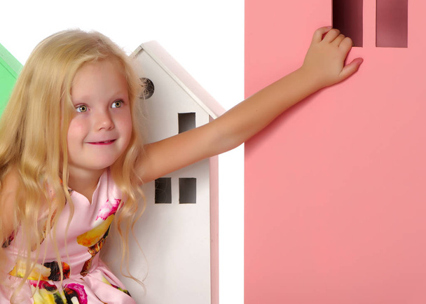Little girl is playing with wooden houses. - Foto, imagen