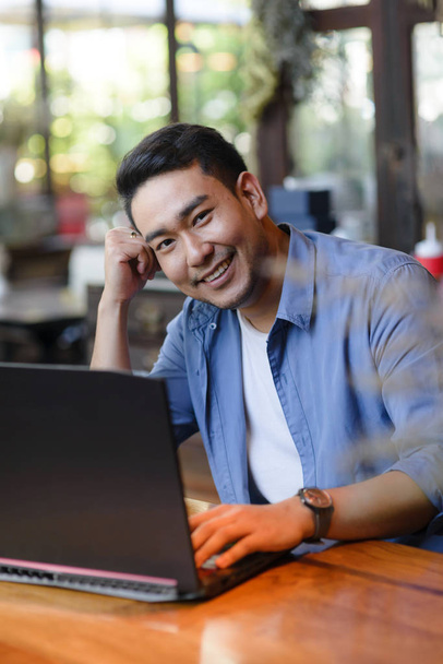 Asian man working with laptop in cafe, work concept. - Foto, Bild
