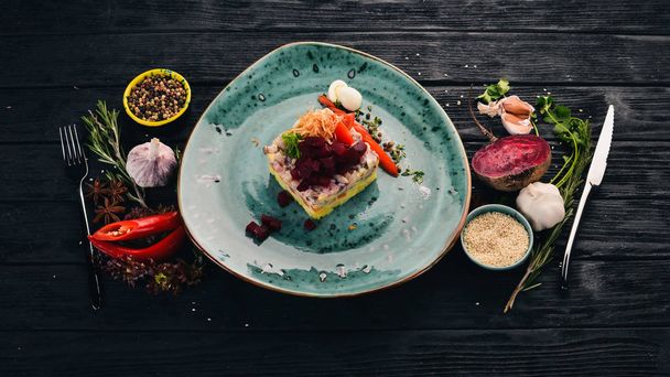 Russian traditional cuisine. Shub salad with herring. Top view. On a black wooden background. Copy space. - Valokuva, kuva