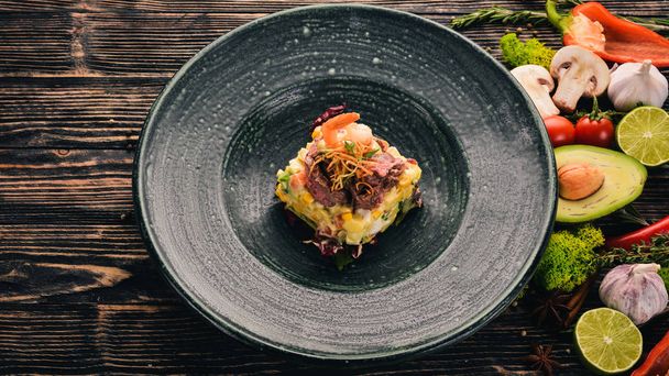 Beef and Shrimp Olivier Salad. Top view. On a black wooden background. Copy space. - Foto, Imagem