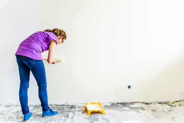 Woman painter painting the wall with paint brush. - 写真・画像