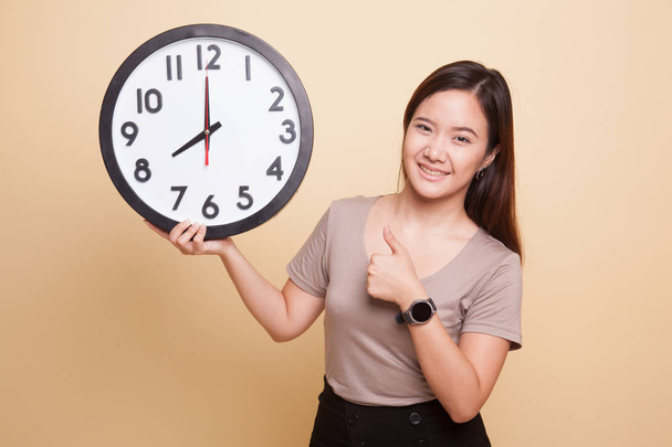 Young Asian woman thumbs up with a clock. - Zdjęcie, obraz