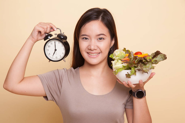 Young Asian woman with clock and salad. - Fotografie, Obrázek