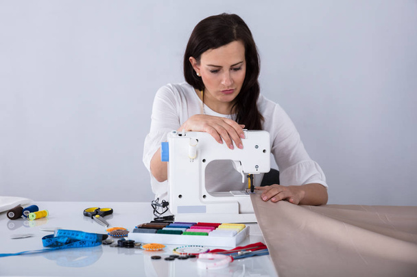 Young Female Fashion Designer Stitching Fabric On Sewing Machine In Studio - Foto, immagini