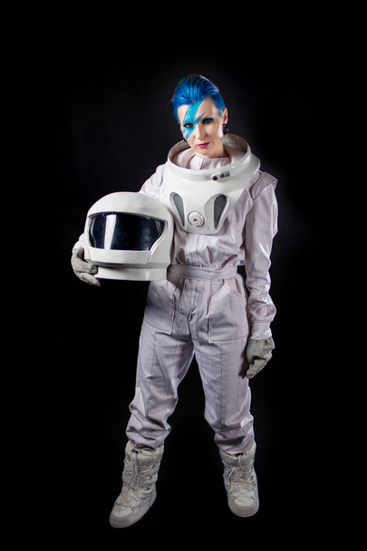 Astronaut on a black background, a young woman with face art in the space suit. Helmet in hands - Foto, Bild