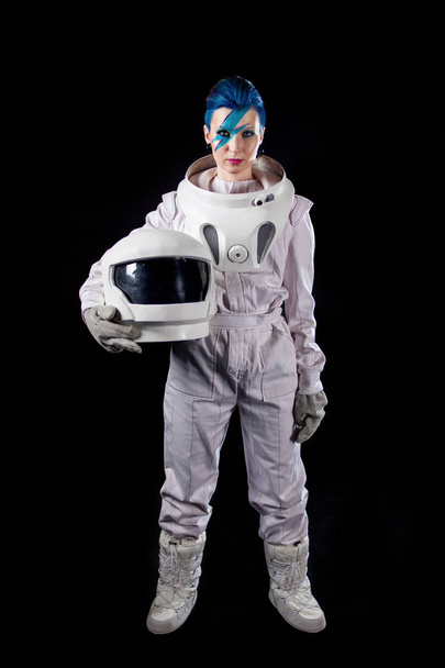 Astronaut on a black background, a young woman with face art in the space suit. Helmet in hands - Photo, Image
