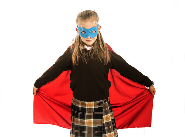 7 o 8 anni giovane bambina in costume da supereroe sopra uniforme scolastica esibendosi felice ed eccitato isolato su sfondo bianco
 - Foto, immagini