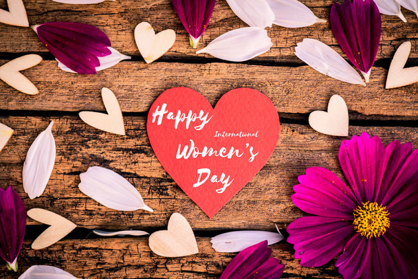 Wiadomość dnia 8 marca szczęśliwe kobiety na drewniane tła z serce czerwone i białe i fioletowe kwiaty. - Zdjęcie, obraz