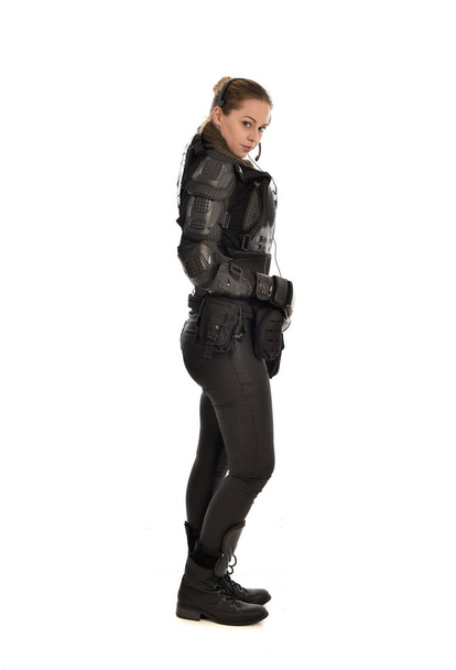 portrait complet de soldat féminin portant une armure tactique noire, debout de profil, isolé sur fond de studio blanc
. - Photo, image