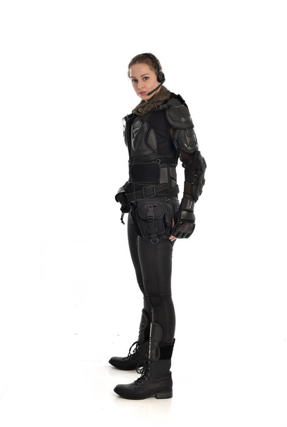 full length portrait of female  soldier wearing black  tactical armour, standing in profile, isolated on white studio background. - Photo, Image