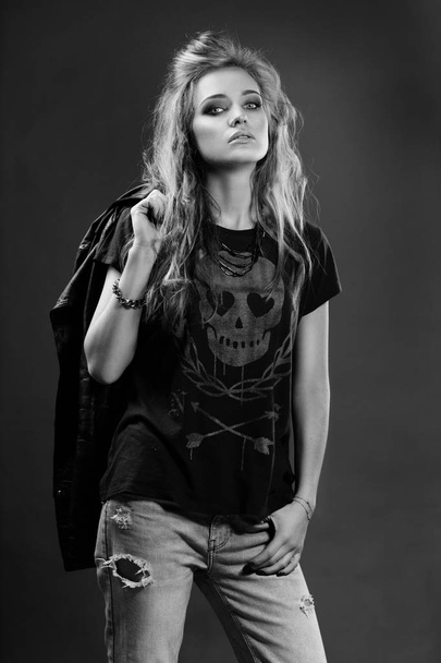 black and white portrait of a charismatic female rocker with a leather jacket thrown back across the arm  - Foto, imagen