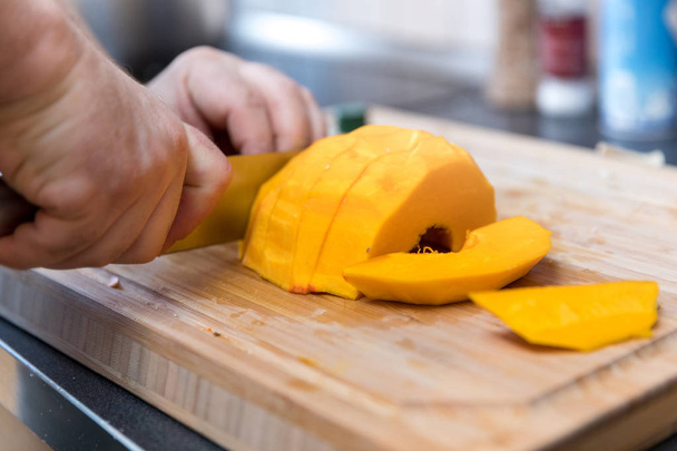 cutting pumpkin on wooden cutting board - Фото, изображение