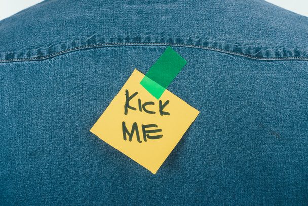 close up view of note with kick me lettering on jeans shirt, april fools day concept - Photo, Image