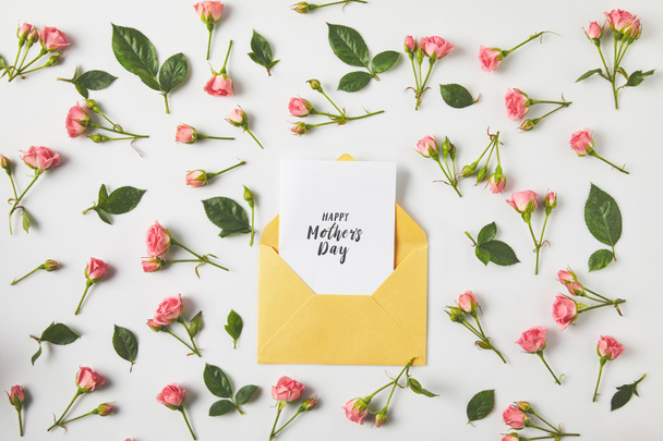 happy mothers day greeting card in envelope and beautiful pink roses and green leaves on grey   - Foto, imagen