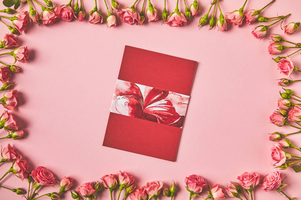 top view of frame made from beautiful pink roses and greeting card on pink - Fotoğraf, Görsel