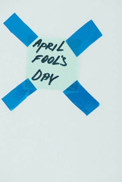 close up view of note with april fools day lettering and sticky tapes isolated on grey, april fools day concept - Foto, imagen