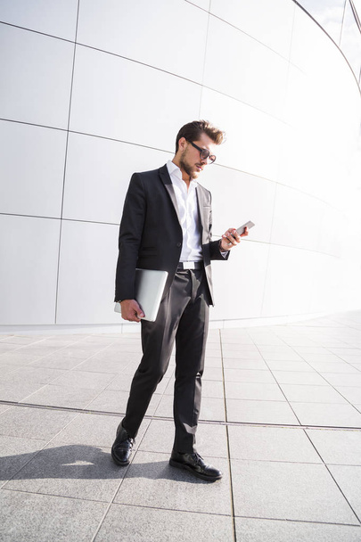 Male businessman or worker in black suit with smart phone - Фото, изображение