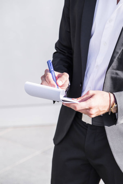 Male businessman or worker in black suit writing in notebook. - Φωτογραφία, εικόνα