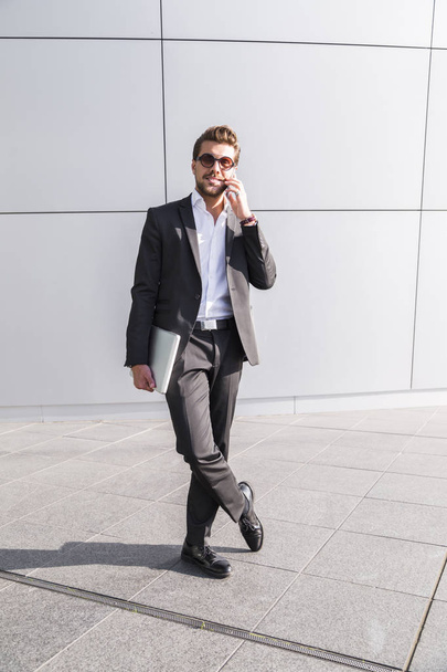 Male businessman or worker in black suit talking on phone - 写真・画像