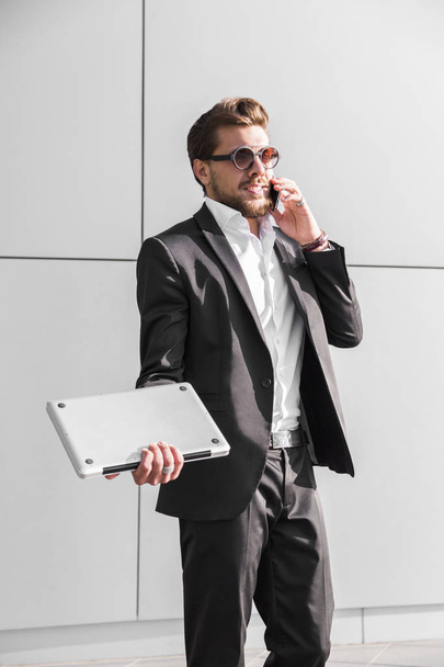 Male businessman or worker in black suit talking on phone - Fotó, kép