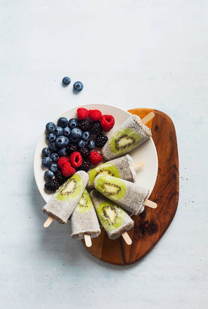 Kiwi Coconut Chia Popsicles and fresh ripe forest berries on the - Foto, immagini