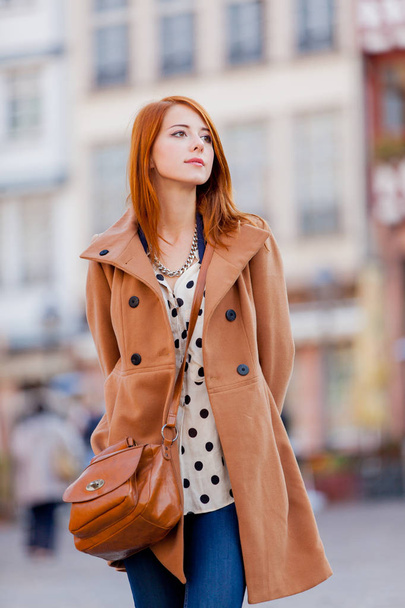 Young redhead woman in coat have a rest on Frankfurt streets, Germany  - Fotó, kép