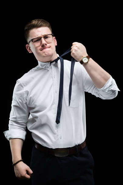 Blonde guy taking off tie on black background - Photo, Image