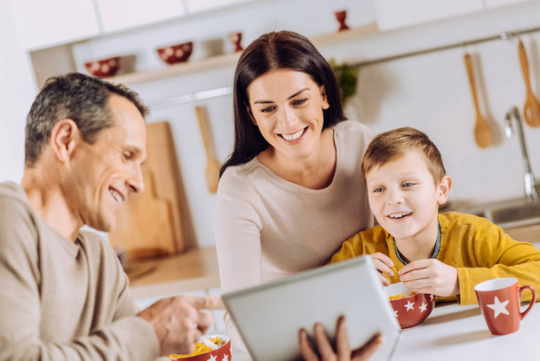 Upbeat father showing tablet to his family during breakfast - Фото, зображення