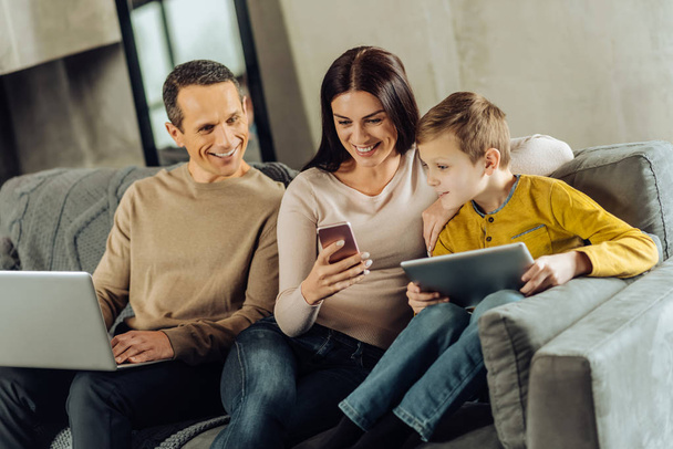 Upbeat woman showing something funny on phone to her family - Foto, Bild