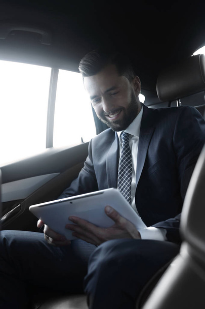 businessman with a digital tablet sitting in the back seat of a car - Fotoğraf, Görsel
