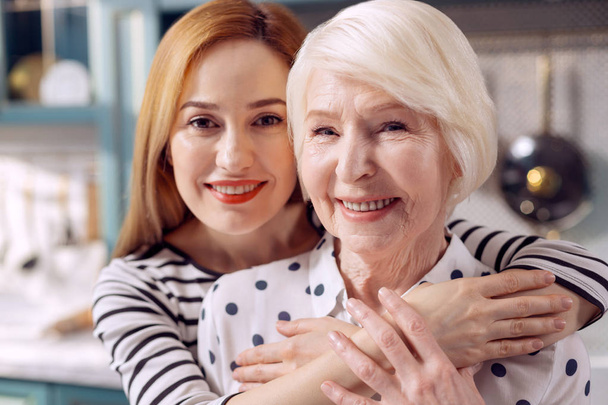 Cheerful daughter and mother hugging and posing - Фото, зображення