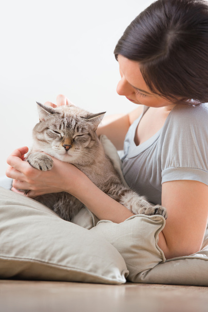 An attractive woman and her cat relaxing on pillows on floor - Foto, Bild