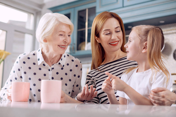 Cute girl telling funny story to her mother and grandmother - Photo, image