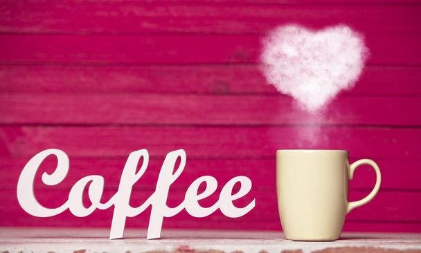 Heart shape steam from beige cup of coffee and word Coffee on pink background  - Photo, Image