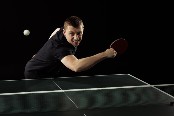 tennista emotivo in uniforme giocare a ping pong isolato su nero
 - Foto, immagini