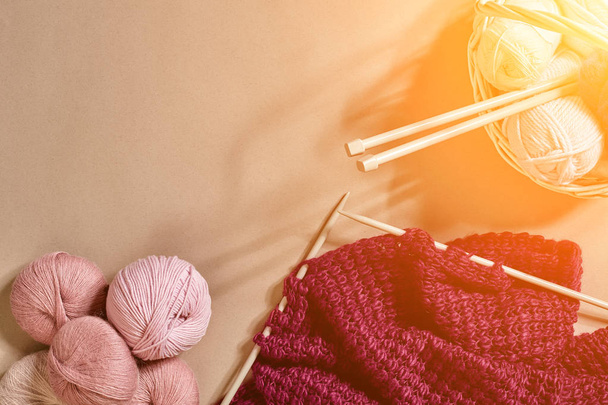 Balls of merino wool yarn, knitting on knitting needles on a beige surface. Top view. Sun flare - Fotografie, Obrázek