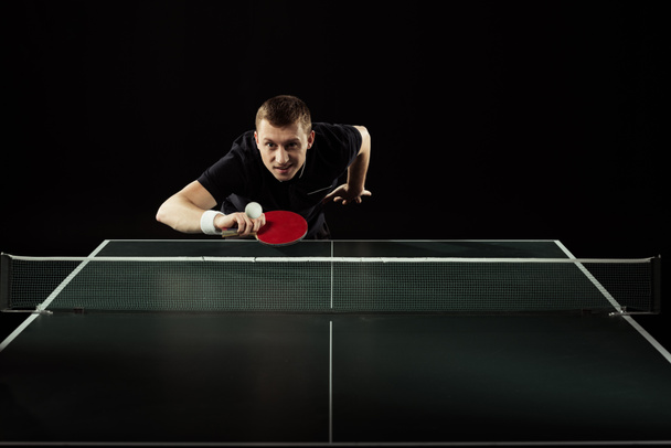 portrait of tennis player in uniform playing table tennis isolated on black - Photo, Image